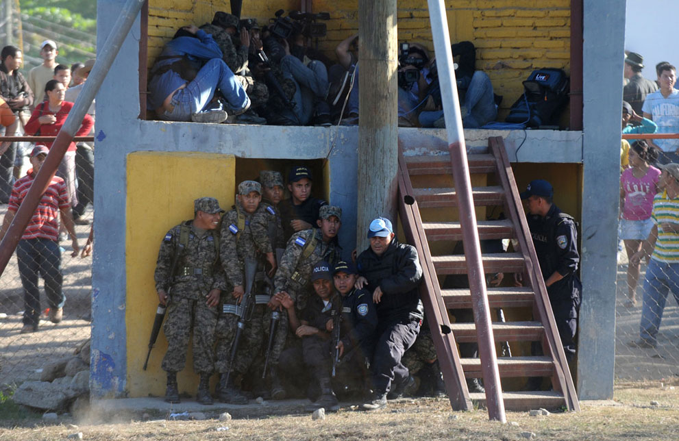 پلیس و خبرنگاران پناه گرفته از درگیری زندانیان هندوراس پس از آتش سوزی در زندان