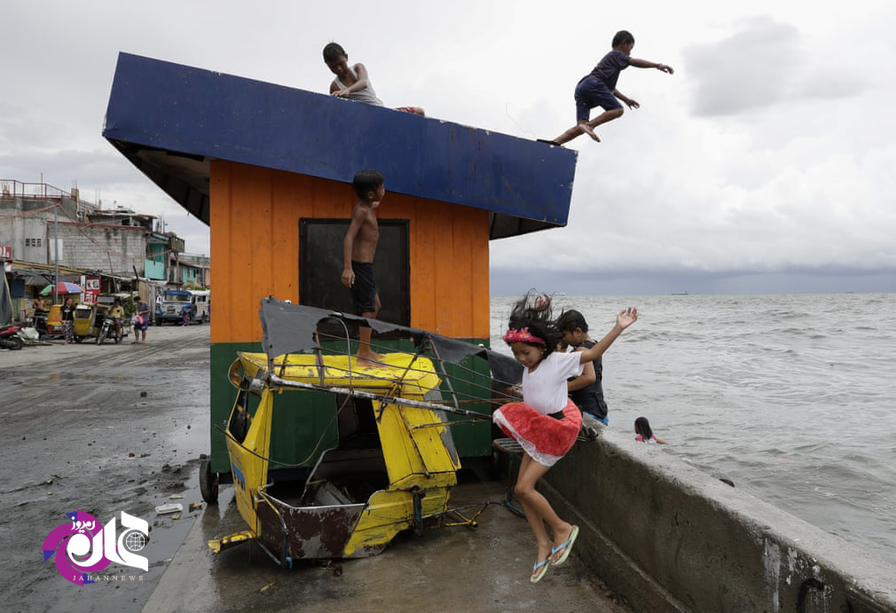 کودکان فیلیپینی پس از یک بارندگی شدید در حال شنا کردن هستند.مدارس در این منظقه به دلیل طوفان های گرمسیری به حالت تعلیق در آمده است.